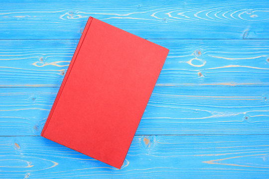 Old Red Book On Wooden Plank Background. Blank Empty Cover For Design