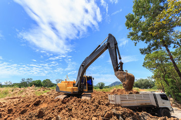 Excavator digging to moving the soil to the truck and adjusting ground level in construction site.