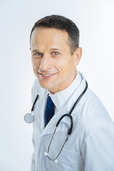 Cheerful mature physician looking into camera with smile on face