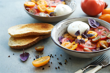 Caprese salad of colorful tomatoes. Tomatoes, mozzarella, basil and spices. Mediterranean cuisine, Italy 
