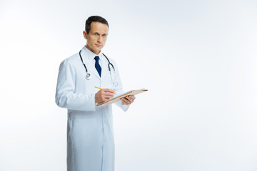 Mature medical worker posing while making notes