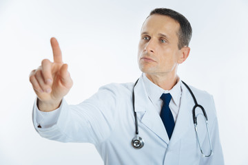 Fototapeta premium Serious mature doctor using invisible touchscreen alone