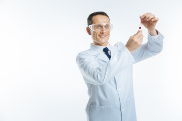 Radiant doctor looking at glass tube with blood sample
