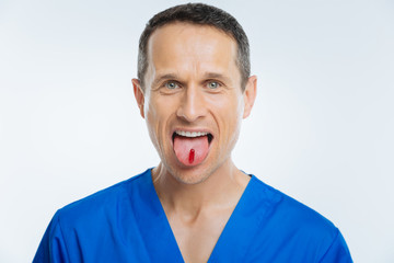 Excited medical worker showing tongue with pill