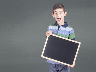 Excited little boy holding a blank chalkboard with copy space