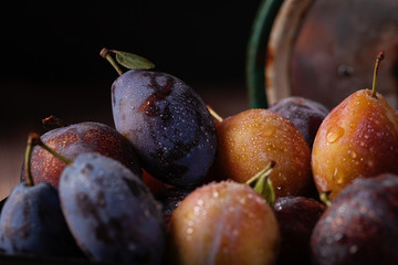 Purple, blue and yellow plums on a wooden table