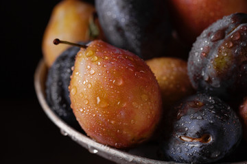 Purple, blue and yellow plums on a wooden table