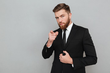 Confident handsome businessman in suit pointing finger at camera