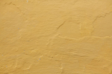 Yellow ochre painted stucco wall. Background texture
