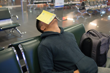 Man sleeping in the airport with book on face