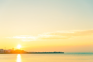 Naklejka premium people on rock pier with calm sea at sunset in italian town of trieste