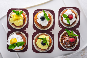 Cakes with fresh fruits and cream filling. On a wooden background. Top view. Free space for text.