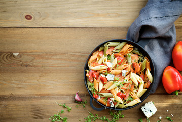 Multicolored penne pasta with vegetables. Roasted red bell pepper, tomatoes, garlic and young parsley 
