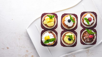 Cakes with fresh fruits and cream filling. On a wooden background. Top view. Free space for text.