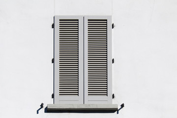 Closed shutter window on a white wall
