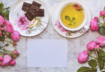 Obraz na płótnie Canvas Vintage mockup. Blank paper, tea cup and dark chocolate, pink roses. Wedding invitation