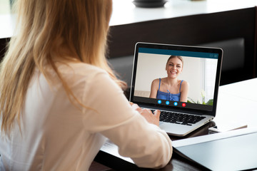 Two young women chatting online by making video call on laptop, using videoconferencing app for...