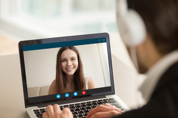 Fototapeta na wymiar Smiling girl on videocall with guy, making video call to close foreign friend, talking by web camera, using virtual chat app online, long distance relationships, focus on screen, close up rear view