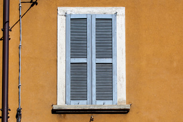Closed vintage shutter window on a ocher wall