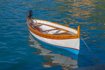 Wooden fishing boat isolated with reflexes on the sea water