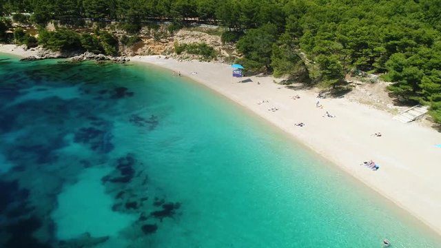 Aerial lateral view of people swimming and sunbathing on Zlatni Rat, on the island of Brac, Croatia. 