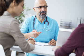 Male doctor talking to young couple