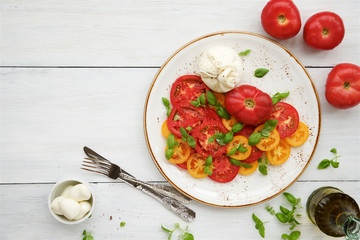 Fresh tomato salad with burrata cheese (mozzarella) and basil. White wooden rustic table
