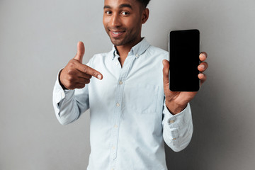 Excited man pointing finger at blank screen mobile phone