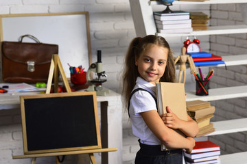 Back to school concept. Schoolgirl holds book on classroom background