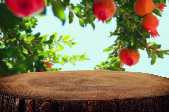 vintage wooden board table in front of dreamy pomegranate tree.