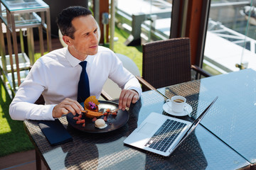 Positive handsome man enjoying his breakfast