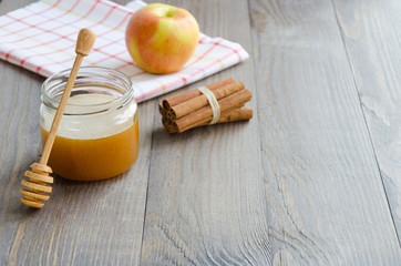 Jar of honey, honey stick, cinnamon and red apple