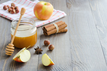Jar of honey, honey stick, cinnamon, hazelnuts and red apple