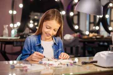 Charming teenage girl choosing nail polish color
