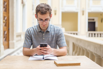 Young student guy learning and use his phone