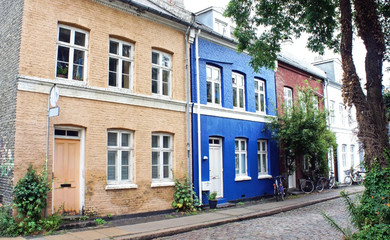Street in old town, stone wall, blue and beige color buildings, traditional houses, Copenhagen, Denmark