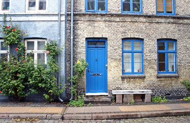 Street in old town, stone wall, blue color windows and door, traditional houses, Copenhagen, Denmark. 