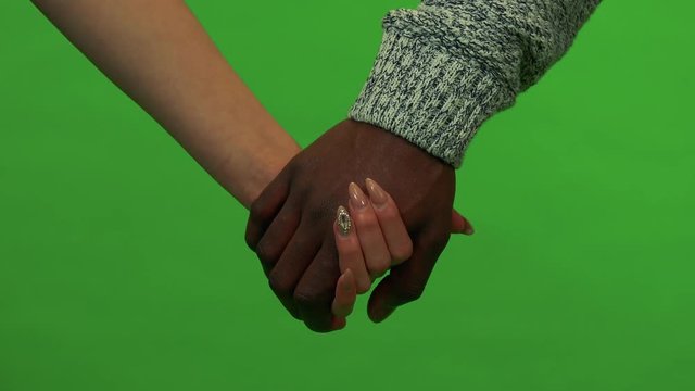 An Asian woman and a black man hold hands - closeup - green screen studio