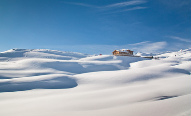 Sunny valley refuge over Santa Caterina Valfurva in winter into the snow