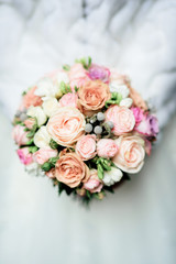 Stunning wedding bouquet made of roses and peonies lies on white cloth