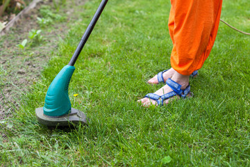 Garden equipment. Woman mowing the grass with a trimmer