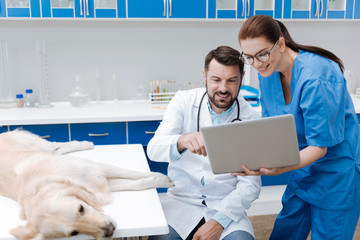 Positive delighted lab assistant holding laptop