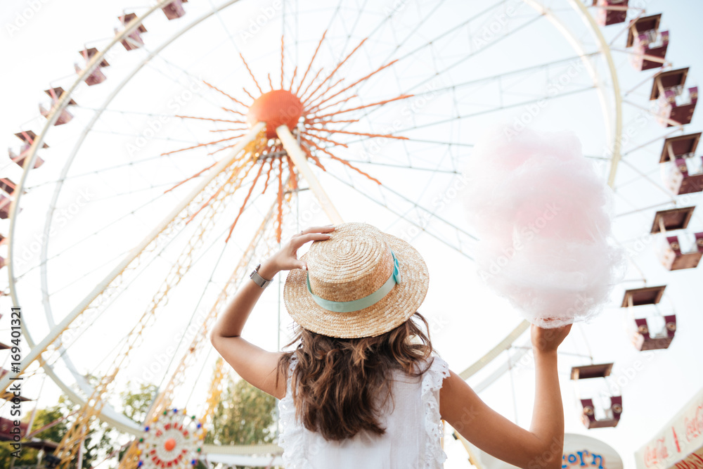 Canvas Prints Back view of a girl in hat holding cotton candy