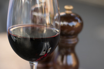 Close-up: Cutlery set reflected in a glass of red wine on a table for a start. Good red wine is one of a favorite classic alcoholic beverages in the world.