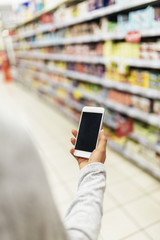 Close up of woman using her mobile in supermarket.