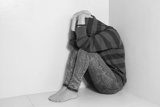 Black and white picture of depressed girl sitting on the floor, upset, sad, unhappy
