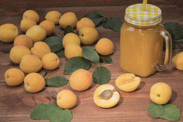 Fresh apricots on a wooden table with leaves and a basket