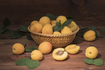 Obraz na płótnie Canvas Fresh apricots on a wooden table with leaves and a basket