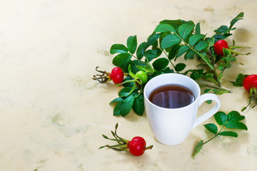 Obraz na płótnie Canvas Tea from a dogrose in a mug on a light background with fruits