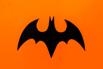 Halloween concept. Handmade black paper bat on orange background. Flat lay, top view.